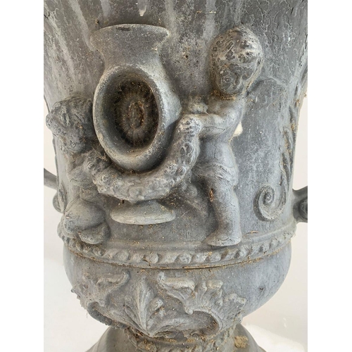 38 - Lead garden oval urn on base with cherub decoration and scrolled handles. {76 cm H x 50 cm W x 38 cm... 
