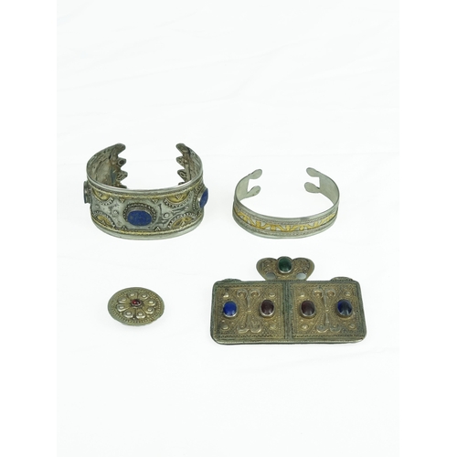 A Set Of Turkmen Tribal Silver Jewellery, Turkmenistan, Central Asia, 19th Century 
Consisting of two cuffs, one amulet and one button, the cuffs (called bilarzik) with lapis lazuri insets and intricate decoration, large rectangular amulet inlaid with natural stones with fretwork, small circular button  inlaid with natural stone and fret work, 101gram, large cuff 3.8cm wide, small cuff 1.8cm wide, button diameter 3.1cm, amulet 8.3cm x 6.5cm