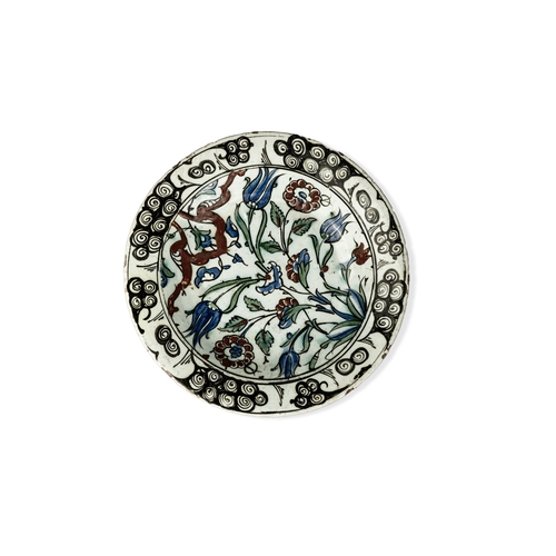 58 - AN IZNIK POLYCHROME POTTERY DISH, TURKEY, CIRCA 

Of rounded form, decorated in underglaze cobalt bl... 