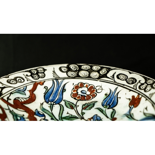 58 - AN IZNIK POLYCHROME POTTERY DISH, TURKEY, CIRCA 

Of rounded form, decorated in underglaze cobalt bl... 