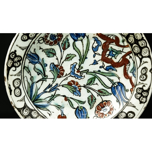 58 - AN IZNIK POLYCHROME POTTERY DISH, TURKEY, CIRCA 

Of rounded form, decorated in underglaze cobalt bl... 