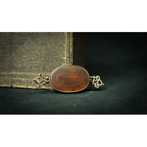 11 - SILVER FRAMED AGATHE OVAL PAZUBAND, AMULET Of oval form, the agate surface engraved with Arabic insc... 