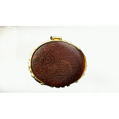 15 - AN ENGRAVED GOLD FRAMED OVAL AGATE PENDANT Of oval form, the agate surface engraved with Arabic insc... 