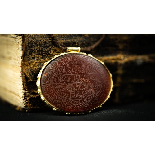 15 - AN ENGRAVED GOLD FRAMED OVAL AGATE PENDANT Of oval form, the agate surface engraved with Arabic insc... 