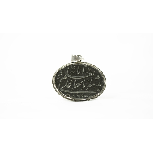 27 - A SILVER FRAMED DARK HARD STONE PENDANT Of oval form, the surface engraved with Persian nasta’liq in... 