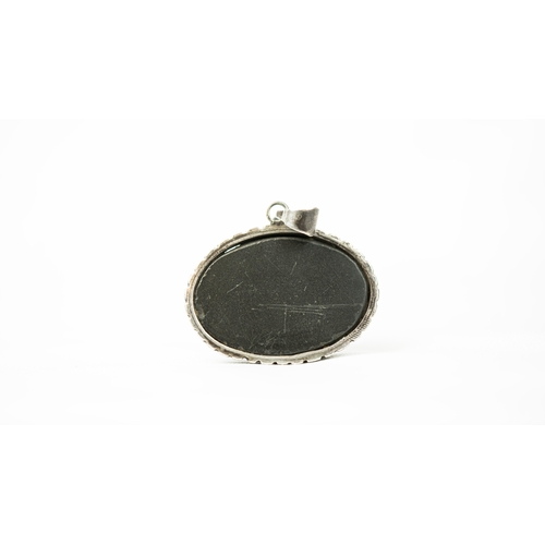 27 - A SILVER FRAMED DARK HARD STONE PENDANT Of oval form, the surface engraved with Persian nasta’liq in... 