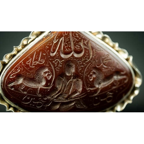 4 - A SILVER FRAMED CARVED AGATE PENDANT IRAN, TAHRAN. Of wide drop form, depicting Imam Ali with Zulfik... 