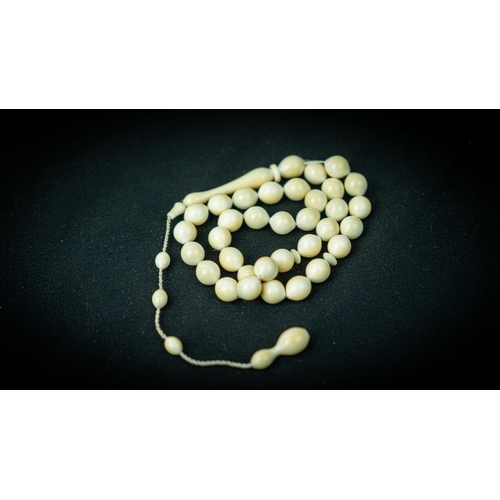 53 - A BONE PRAYER BEADS, The tasbih strung  with 33 bone spherical  beads, flat stops, narrowing and  el... 