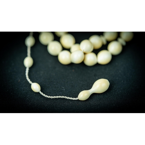 53 - A BONE PRAYER BEADS, The tasbih strung  with 33 bone spherical  beads, flat stops, narrowing and  el... 