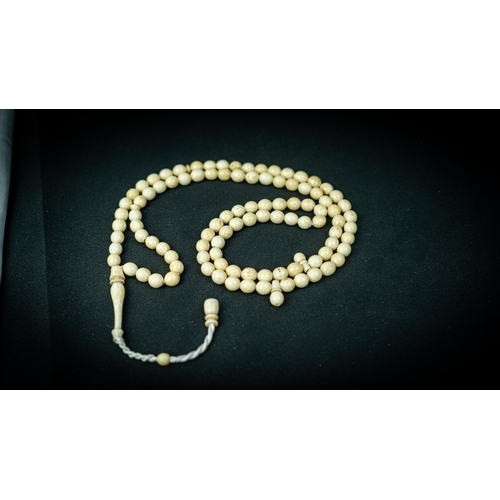 54 - A MORS TOOTH PRAYER BEADS, The tasbih strung  with 99 bone spherical  beads, flat stops, narrowing a... 