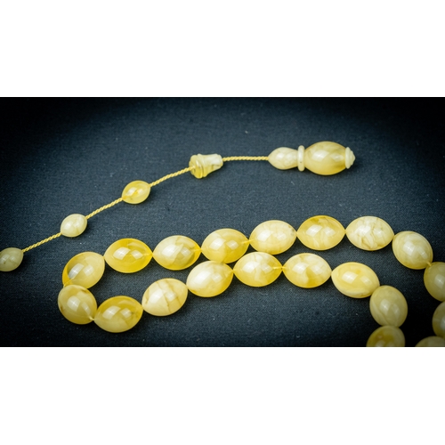 65 - AN AMBER PRAYER BEADS, 20TH CENTURY, The tasbih strung  with 33  ovoid  beads, flat stops, narrowing... 