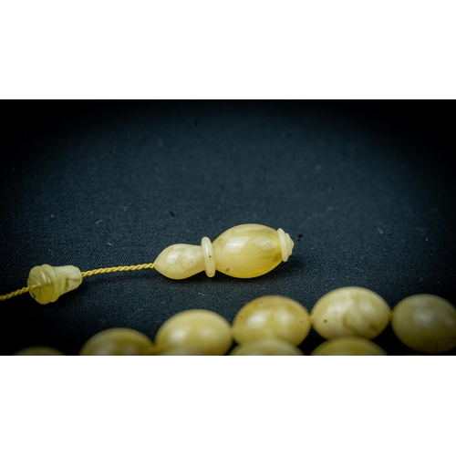 65 - AN AMBER PRAYER BEADS, 20TH CENTURY, The tasbih strung  with 33  ovoid  beads, flat stops, narrowing... 