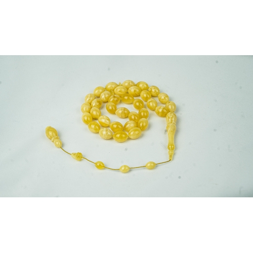 65 - AN AMBER PRAYER BEADS, 20TH CENTURY, The tasbih strung  with 33  ovoid  beads, flat stops, narrowing... 