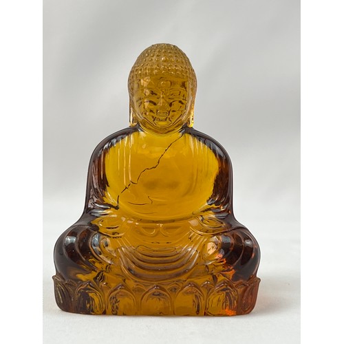 74 - AN AMBEROID STYLIZED BUDDHA ORNAMENT, A serene Buddha, sculpted from  amberoid, resting upon a lotus... 