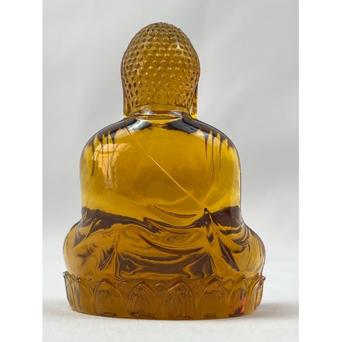 74 - AN AMBEROID STYLIZED BUDDHA ORNAMENT, A serene Buddha, sculpted from  amberoid, resting upon a lotus... 