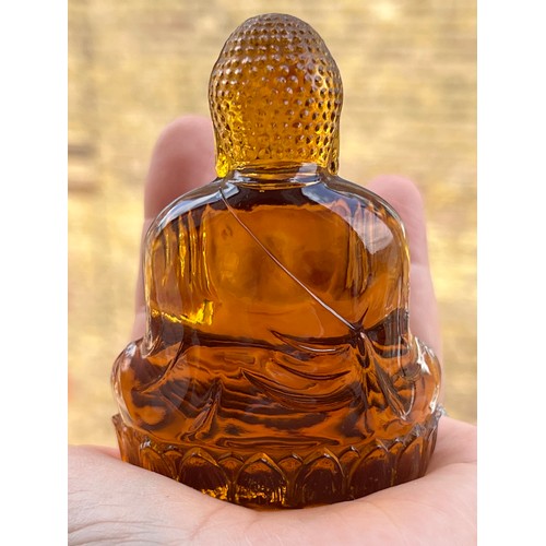 74 - AN AMBEROID STYLIZED BUDDHA ORNAMENT, A serene Buddha, sculpted from  amberoid, resting upon a lotus... 