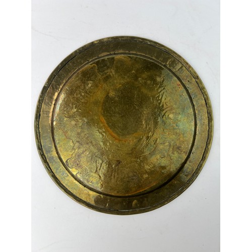 1 - A  BRASS ENGRAVED TRAY

Of circular shape, resting on a flat and plain base, rising to an everted ri... 