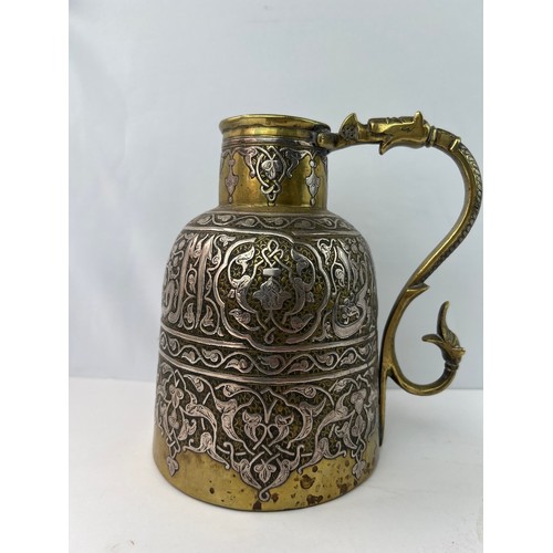 2 - A BRONZE BRASS JUG

Of cylindrical form, with narrowing shoulders, rising to a tubular neck, an S-sh... 