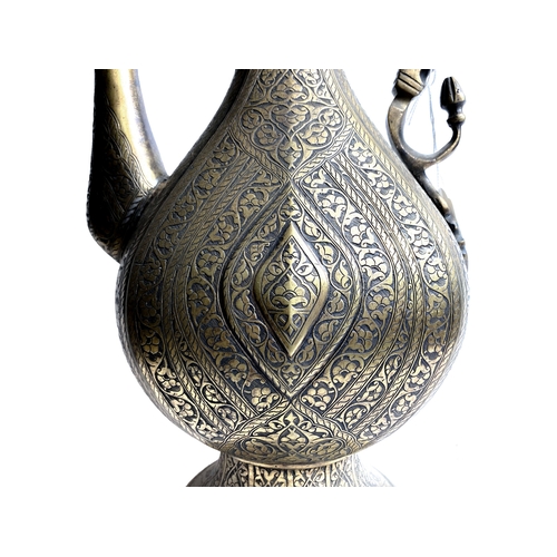 7 - A 19TH 
CENTURY SAFAVID STYLE BRASS EWER

Of tear-drop shape, resting on circular sprayed foot, risi... 