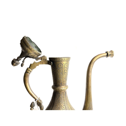 7 - A 19TH 
CENTURY SAFAVID STYLE BRASS EWER

Of tear-drop shape, resting on circular sprayed foot, risi... 