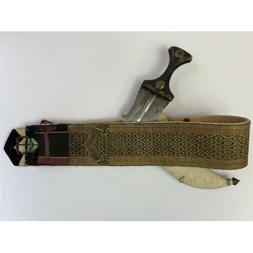 49 - A BRASS JAMBIYA DAGGER WITH A BELT, POSSIBLY OMAN, EARLY 20TH CENTURY

With a double-edged curved st... 