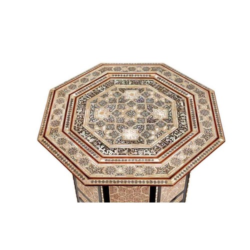 A SYRIAN MOTHER-OF-PEARL, BONE AND PARQUETRY INLAID HARDWOOD OCTAGONAL SIDE TABLE,
DAMASCUS, 20TH CENTURY  Of octagonal shape, resting on bracket feet, intricately inlaid with mother-of-pearl, ebony, stained wood and bone, the top showcasing a central starburst design formed from an eight pointed star, with scattered arabesque patterns and scrolling foliage, encircled with a band of calligraphy in Kufic, the edge adorned with geometric star patterns, the sides with rectangular panels, each showcasing geometric motifs interlacing and radiating to form a central six-pointed star, arched openings on the sides with scrolling foliage with spandrels, a fretwork band along the borders
69cm x 56.5cm