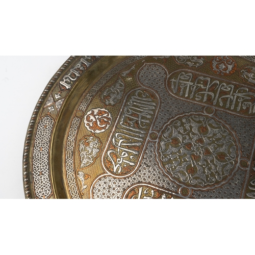 76 - A SILVER-INLAID BRASS TRAY
Of large circular form, resting on a flat, plain base, rising to a flatte... 