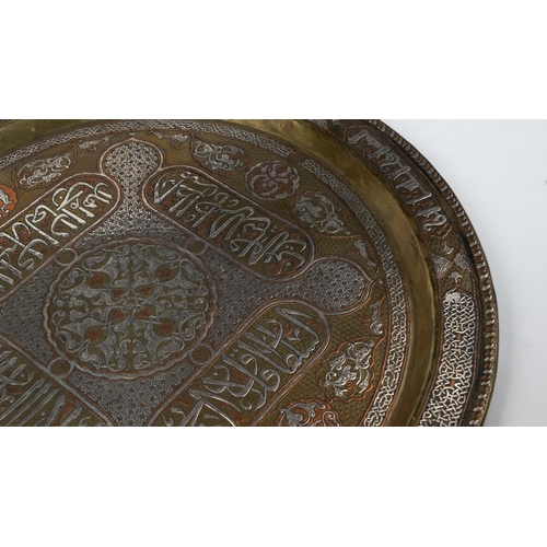 76 - A SILVER-INLAID BRASS TRAY
Of large circular form, resting on a flat, plain base, rising to a flatte... 