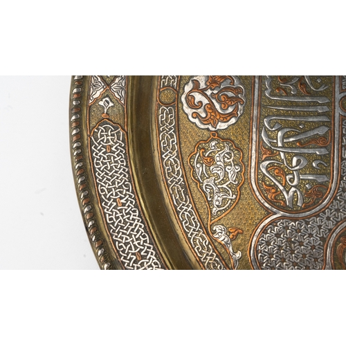 76 - A SILVER-INLAID BRASS TRAY
Of large circular form, resting on a flat, plain base, rising to a flatte... 