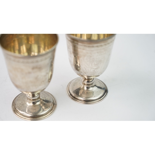 12 - A PAIR OF SILVER CUPS Of rounded circular form, rising from a splayed foot, the body with a palmette... 