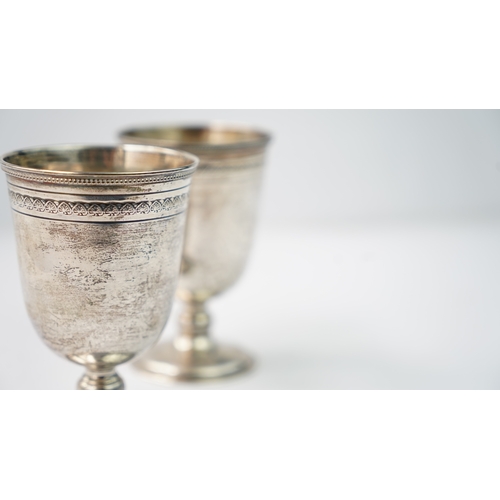 12 - A PAIR OF SILVER CUPS Of rounded circular form, rising from a splayed foot, the body with a palmette... 