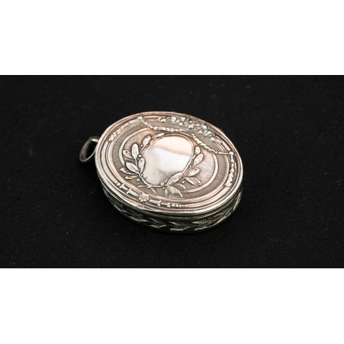 39 - A SILVER PENDANT WITH A HINGED LID  Of oval form, with a hinged lid, featuring a vacant laurel wreat... 