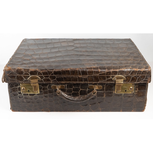 3 - AN EARLY 
20TH CENTURY DARK BROWN CROCODILE LEATHER SUITCASE.Of rectangular form, a travel case feat... 