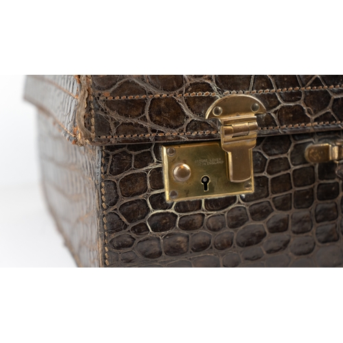 3 - AN EARLY 
20TH CENTURY DARK BROWN CROCODILE LEATHER SUITCASE.Of rectangular form, a travel case feat... 