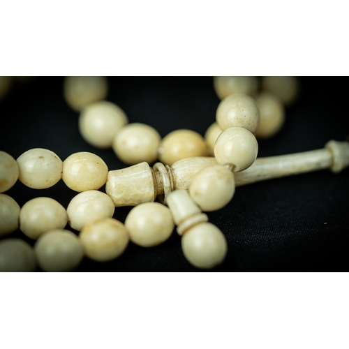 92 - A MORS TOOTH PRAYER BEADS

The tasbih strung  with 99 bone spherical  beads, flat stops, narrowing a... 