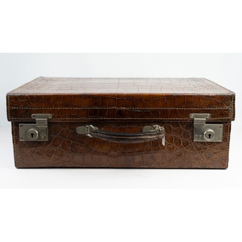 109 - A CROCODILE LEATHER TRAVEL SUITCASE

Of rectangular form, a crocodile travel suitcase in brown hues,... 