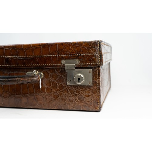 109 - A CROCODILE LEATHER TRAVEL SUITCASE

Of rectangular form, a crocodile travel suitcase in brown hues,... 