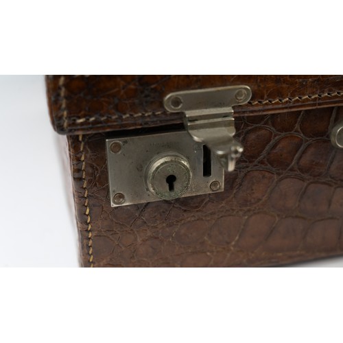 109 - A CROCODILE LEATHER TRAVEL SUITCASE

Of rectangular form, a crocodile travel suitcase in brown hues,... 