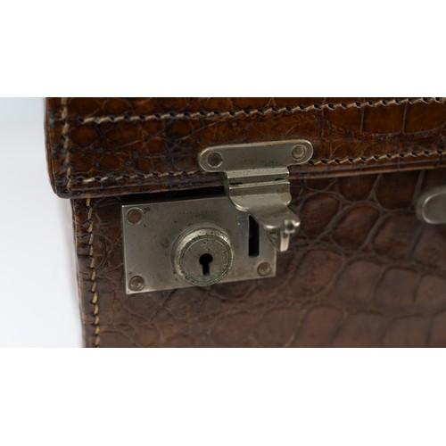 109 - A CROCODILE LEATHER TRAVEL SUITCASE

Of rectangular form, a crocodile travel suitcase in brown hues,... 