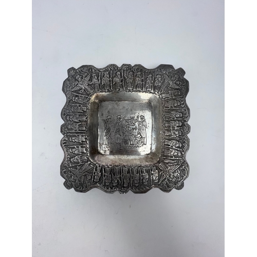 64 - A QAJAR SILVER PLATE, 

Of square form, resting on four bulbous feet, with repoussé and chased decor... 