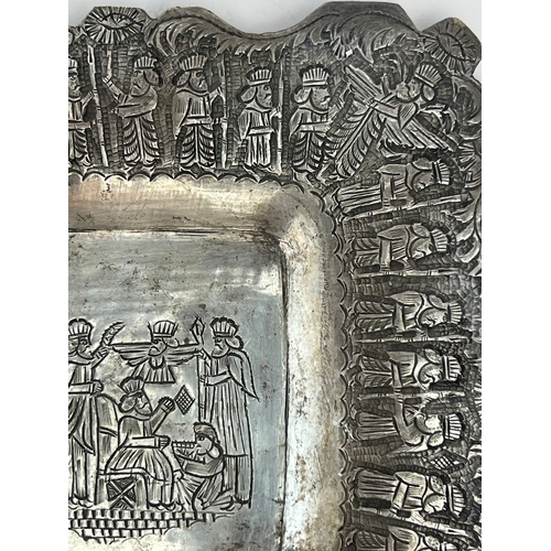 64 - A QAJAR SILVER PLATE, 

Of square form, resting on four bulbous feet, with repoussé and chased decor... 