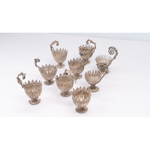 A SET OF NINE SILVER TELKARI ZARF, SALT CELLARS

Each crafted in the form of a blossoming flower, the delicate bowl-shaped receptacle composed of intricately worked filigree petals radiating from a central point,an elaborate openwork handle formed of scrolling foliate motifs, each cellar raised on three splayed feet formed as stylised acanthus leaves, one missing the the crown decoration 

cup 4cm high
with handle 8cm high 

341 grams