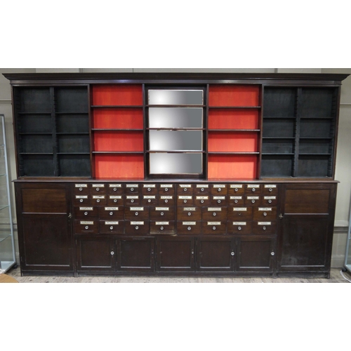 64 - A late 19th century mahogany pharmacy cabinet, having a moulded cornice above three sets of open she... 