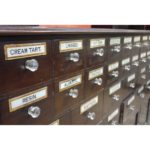 64 - A late 19th century mahogany pharmacy cabinet, having a moulded cornice above three sets of open she... 