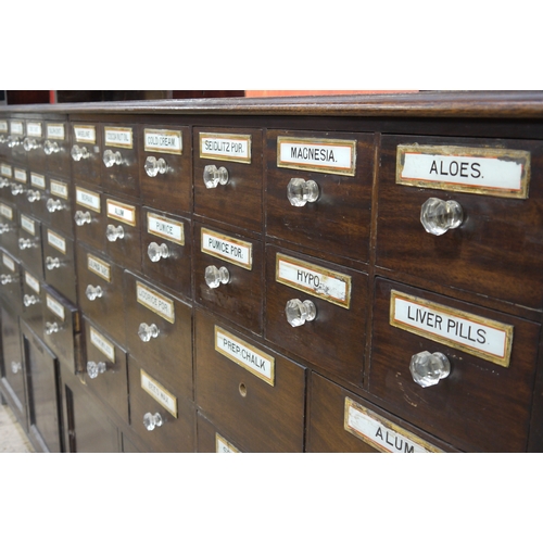 64 - A late 19th century mahogany pharmacy cabinet, having a moulded cornice above three sets of open she... 