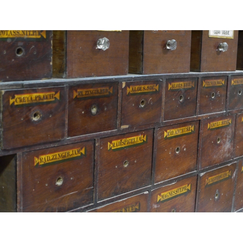 83 - A run of 54 graduated pharmacy drawers in three sections mahogany stained and lettered in black on g... 