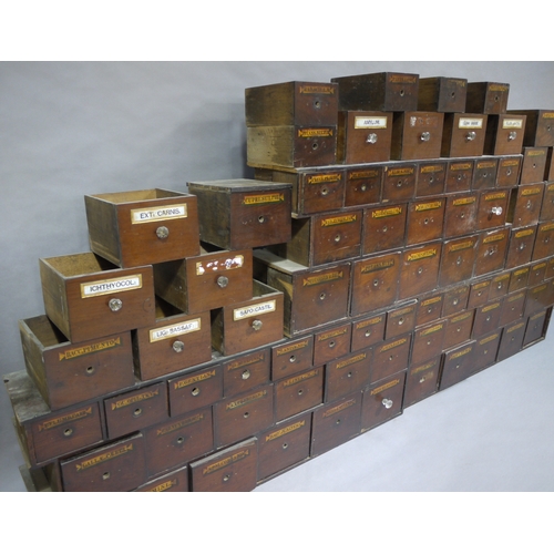 83 - A run of 54 graduated pharmacy drawers in three sections mahogany stained and lettered in black on g... 