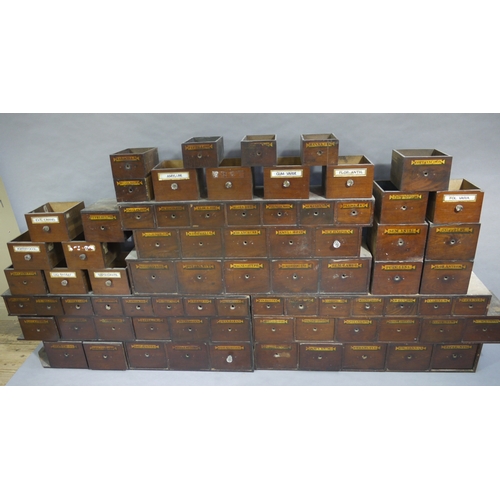 83 - A run of 54 graduated pharmacy drawers in three sections mahogany stained and lettered in black on g... 