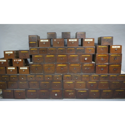 83 - A run of 54 graduated pharmacy drawers in three sections mahogany stained and lettered in black on g... 