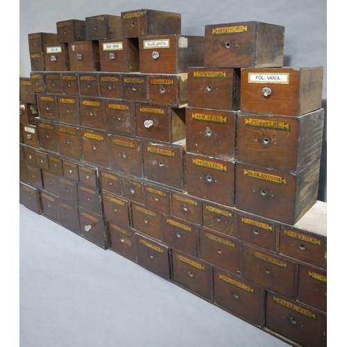 83 - A run of 54 graduated pharmacy drawers in three sections mahogany stained and lettered in black on g... 